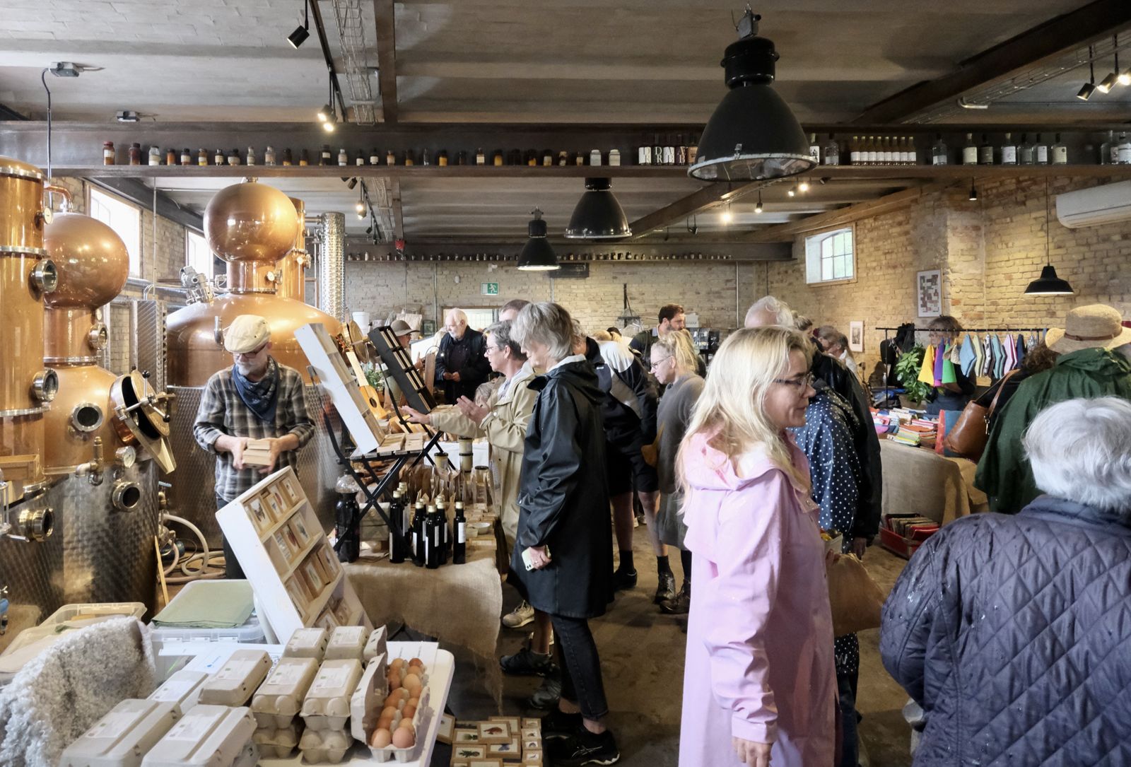 Stader med æg, skind og flasker inde i destilleriet mellem kobberkedlerne